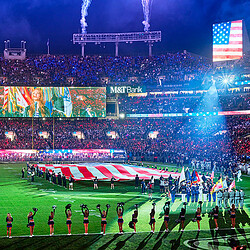 A group of people on a field with a stage and a crowd.