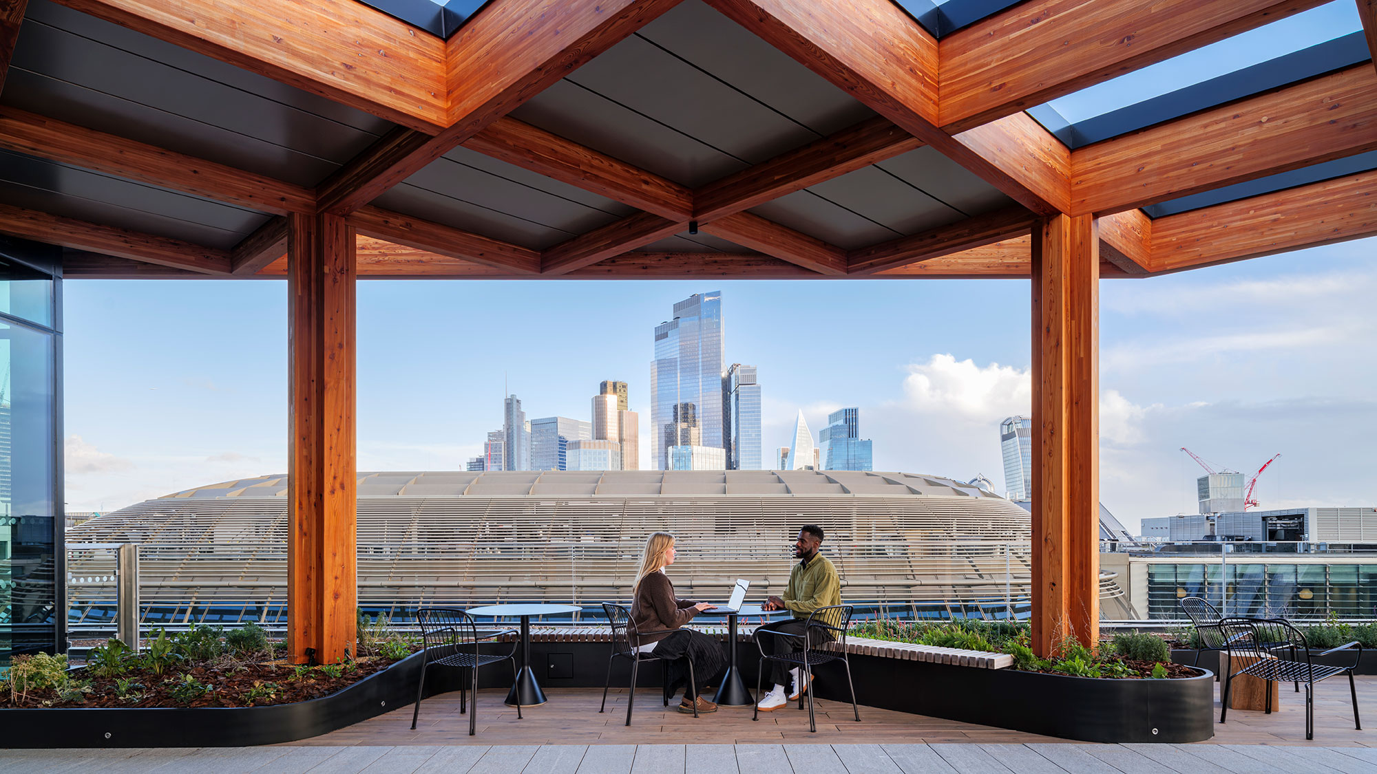 A man and woman sitting at a table with a view of a city.