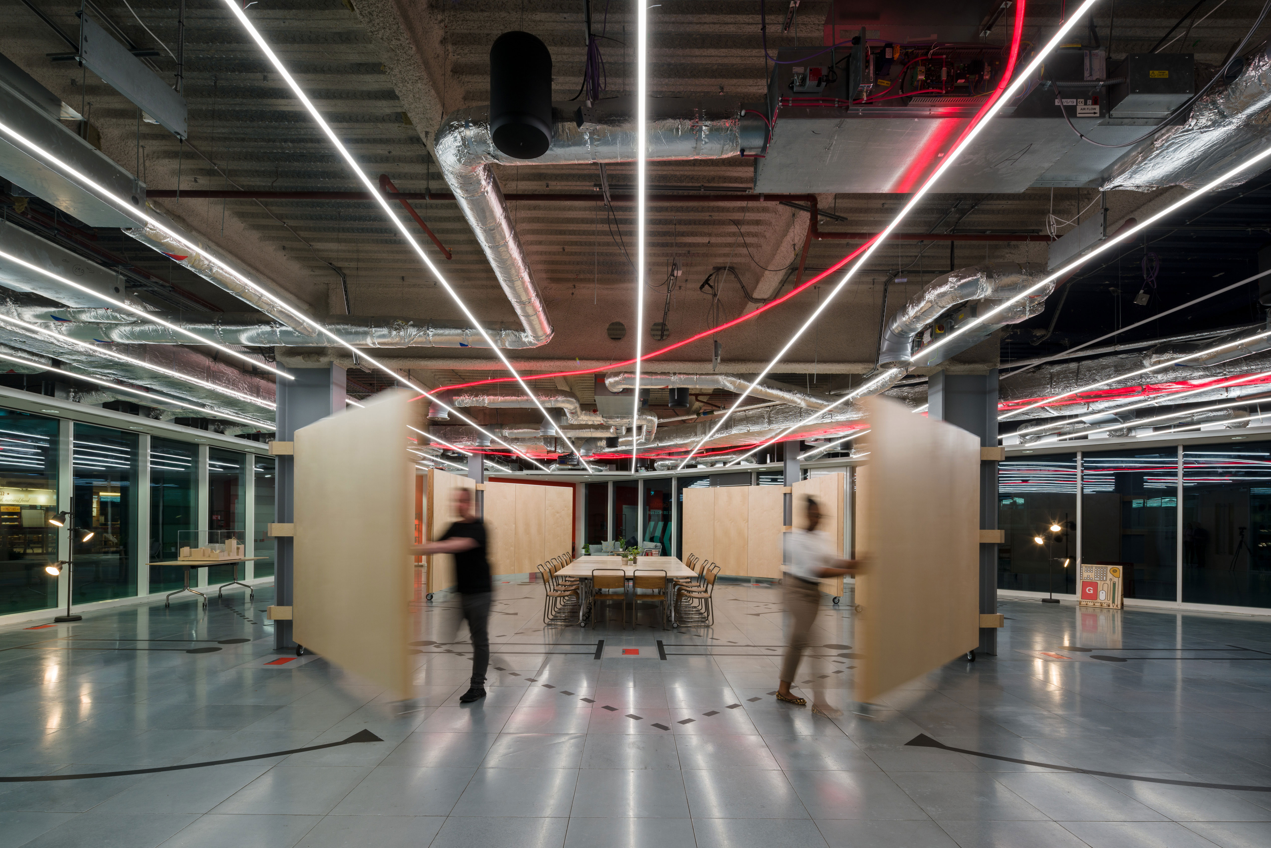 A couple of people walking in a large room with a large ceiling.