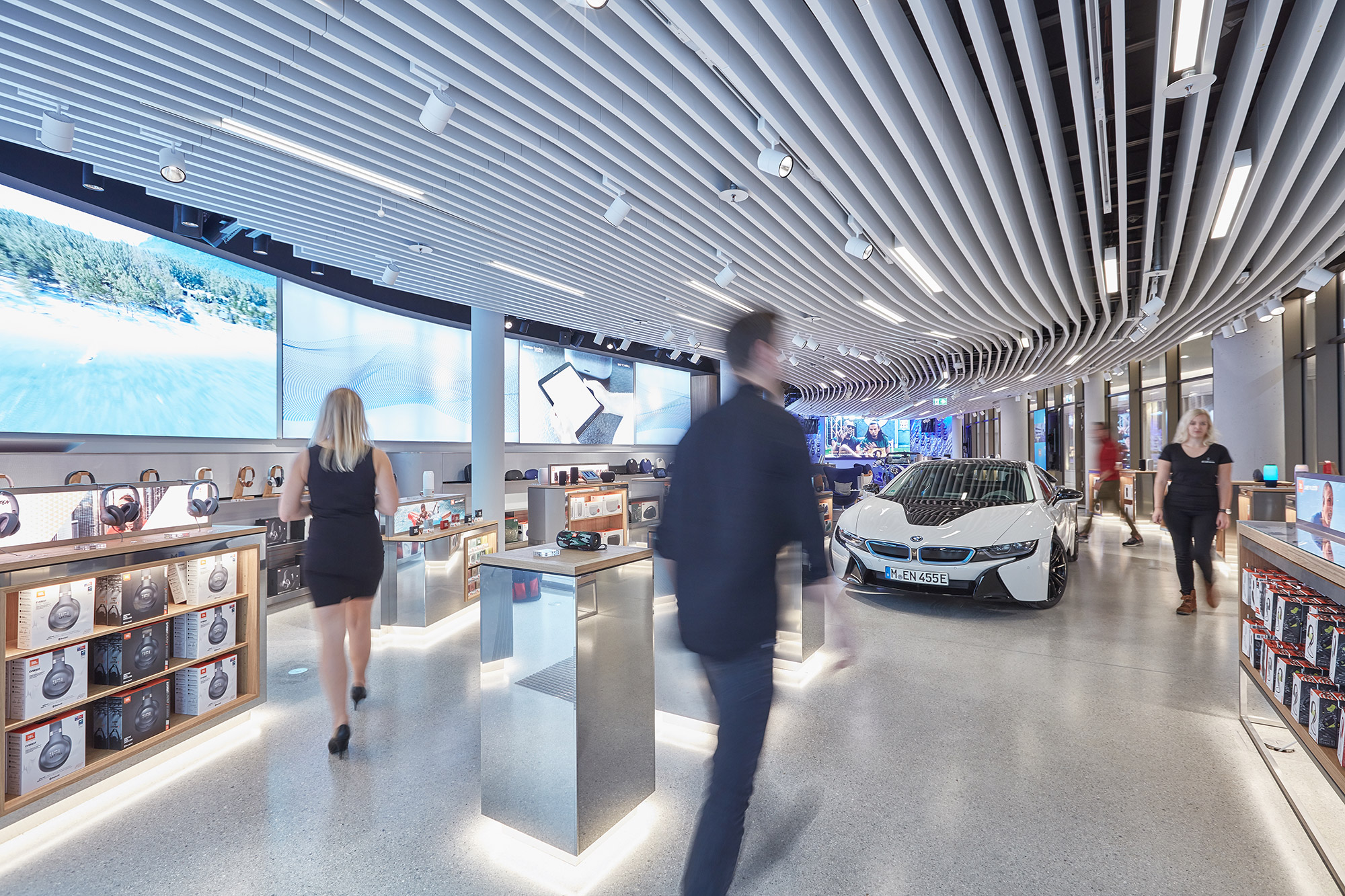 A man and woman in a showroom with a car and a large screen.
