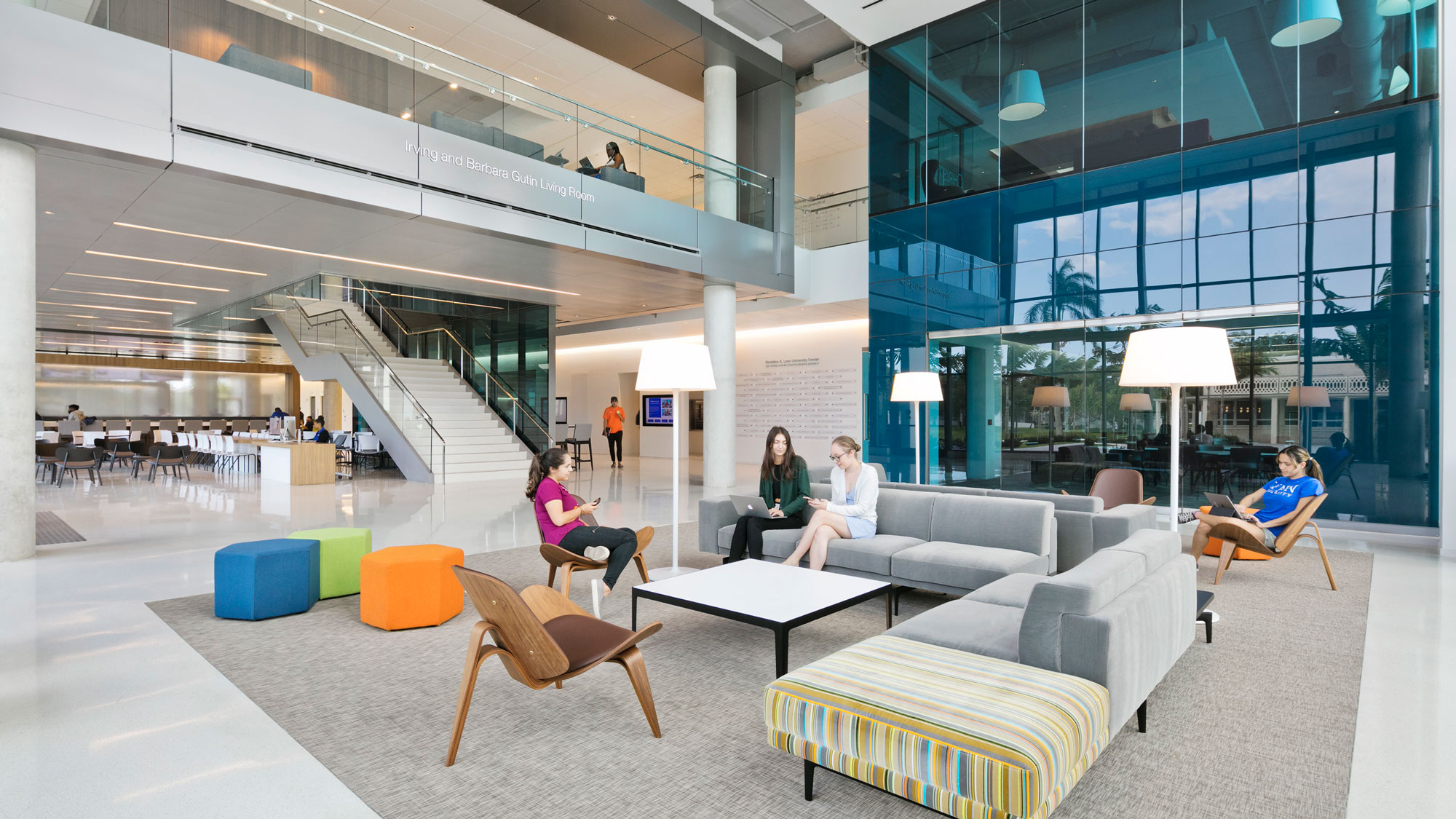 People sitting on couches in a large room with glass walls.