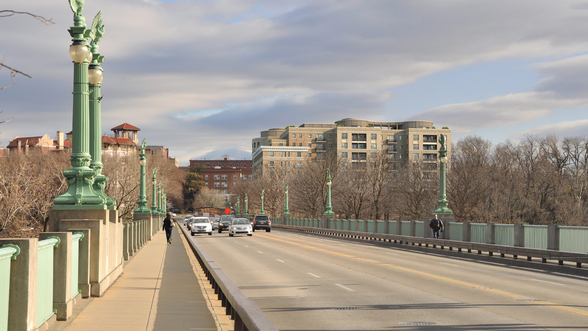 A view of a bridge with two multi-story residential buildings in the distance.