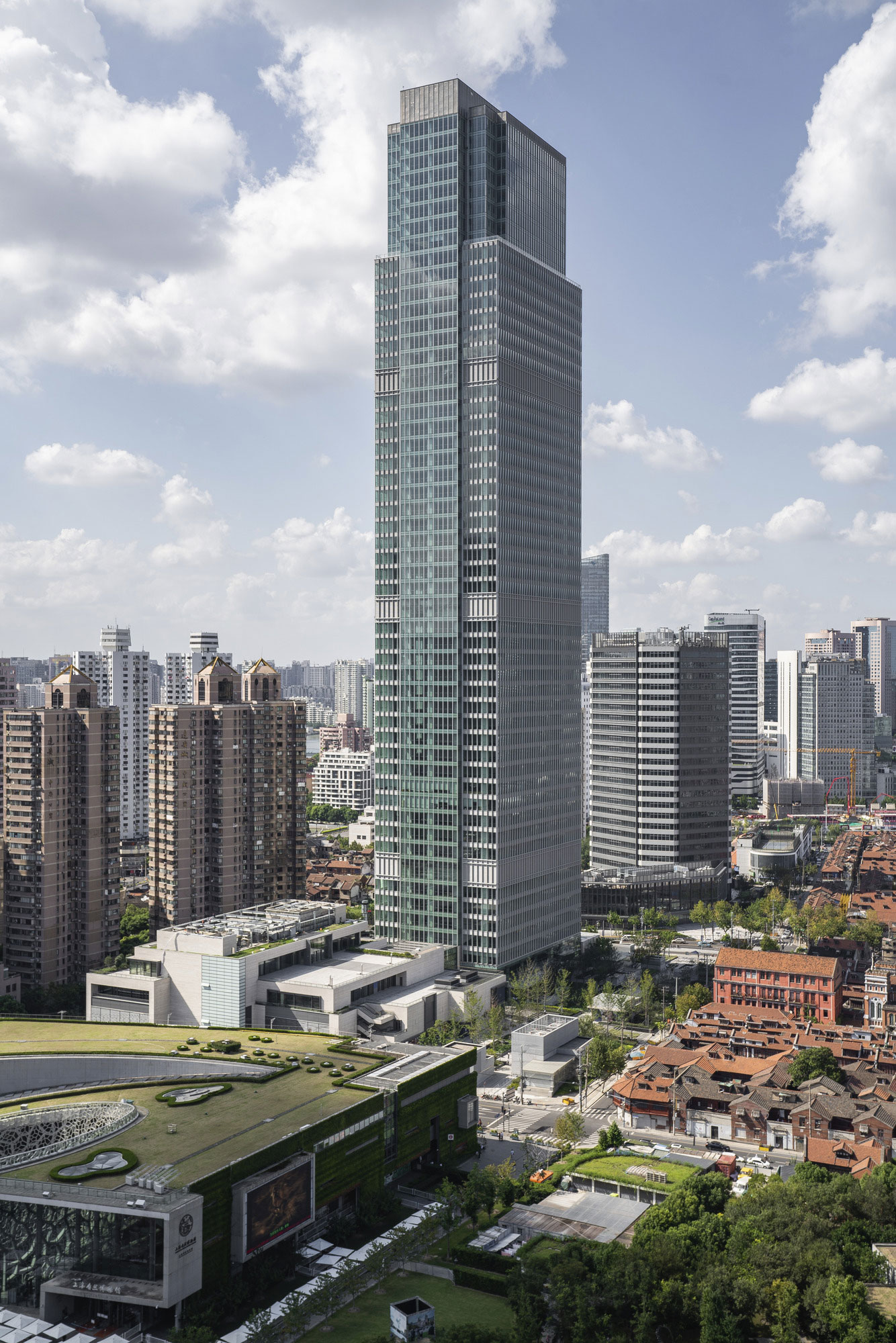 A high-rise glass office tower overlooking the Shanghai Natural History Museum and Jing'an Sculpture Park