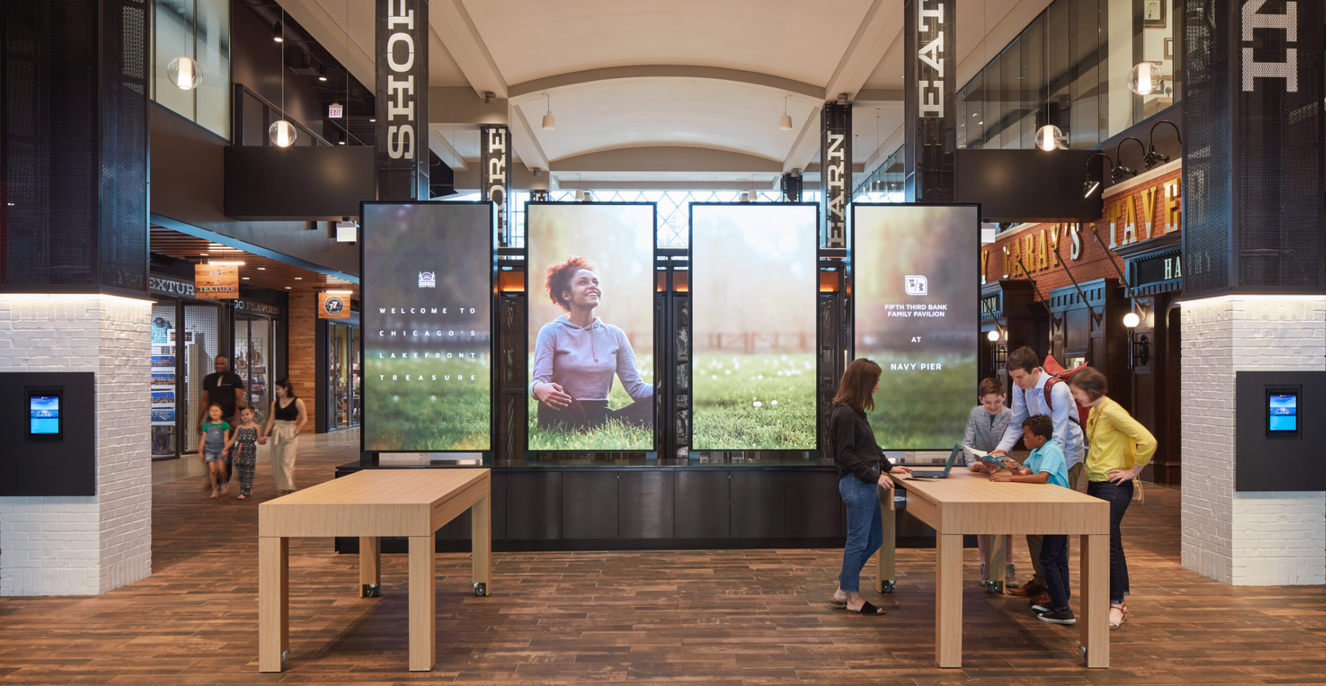 People standing in a room with large screens.