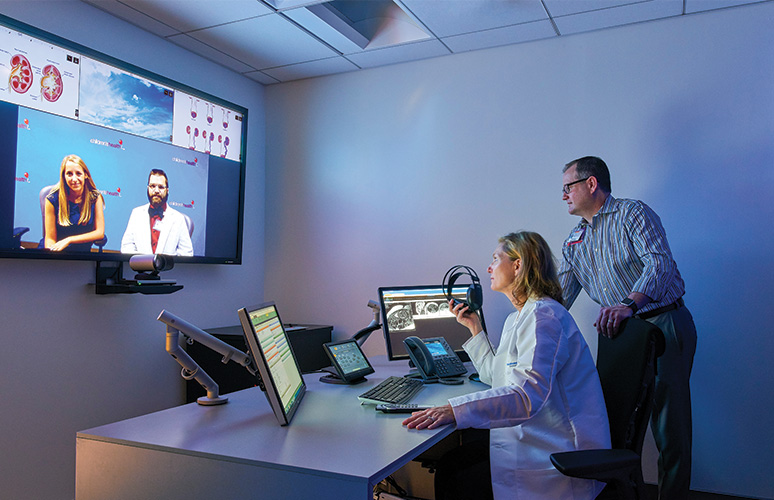 A man and a woman talking to each other in front of computers.