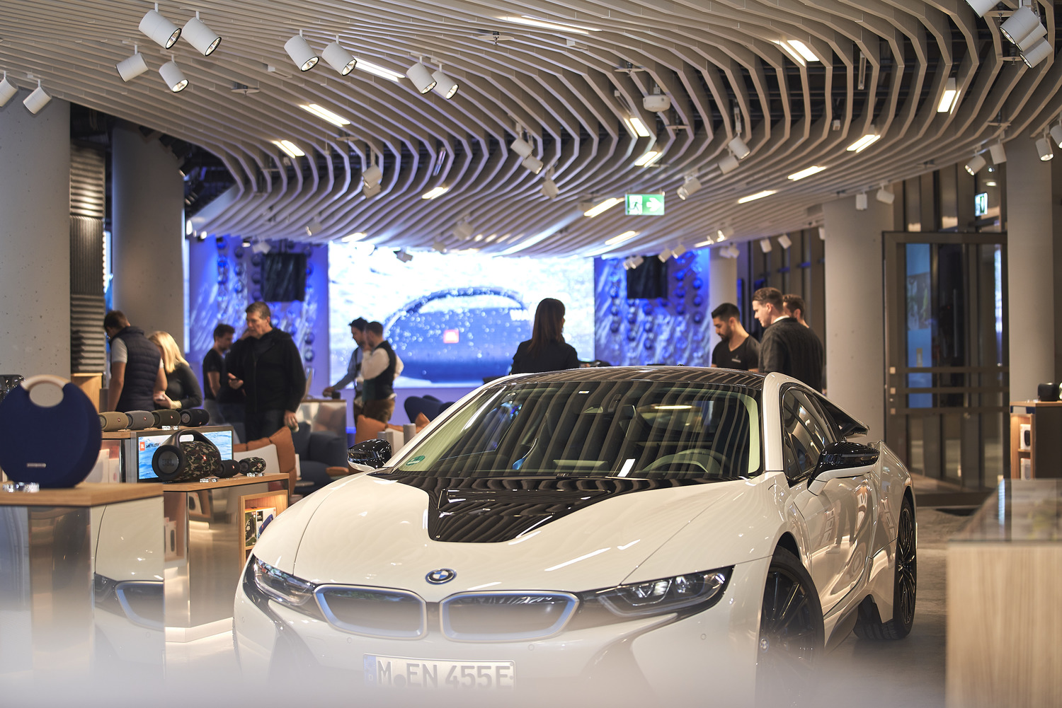 A white sports car in a showroom with people standing around.