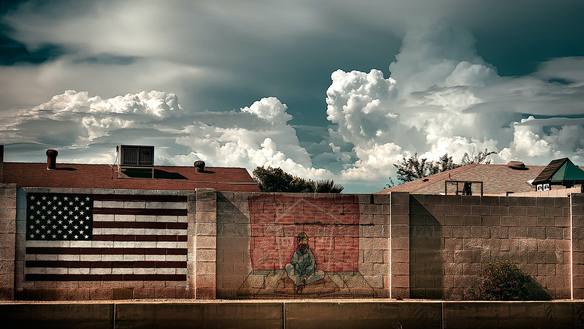 A brick wall with a brick fence and a cloudy sky.