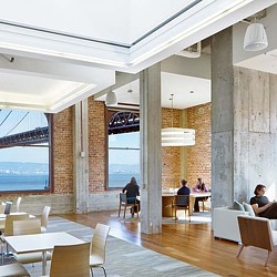 A group of people sitting at tables in a room with a large window.