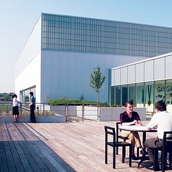 A group of people sitting at a table outside a building.
