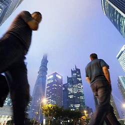 A man and a woman standing on a ledge with a city in the background.