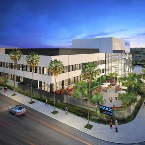 A building with palm trees and people walking around.