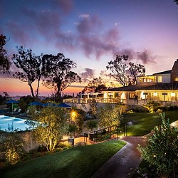 A pool and trees by a building.