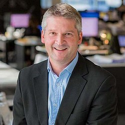 A man in a suit smiling.