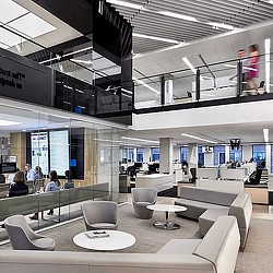 A group of people sitting in a room with white tables and chairs.