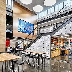 A room with tables and chairs and a large screen.