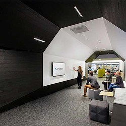 A person standing in a room with people sitting at desks.