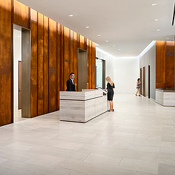 A man and woman standing in a room with a counter and a man sitting at a desk.