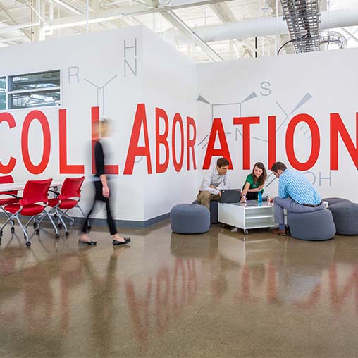 A group of people sitting on couches in a room with a large banner.
