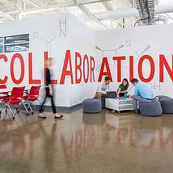 A group of people sitting on couches in a room with a large banner.