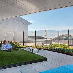 A couple of women sitting on a bench in a large room with a large glass wall and a.