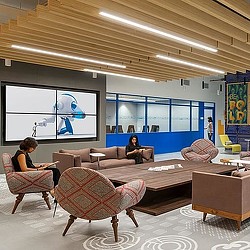 A couple of women sitting in a room with a large screen.