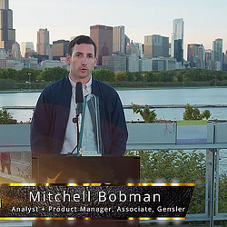 A man standing at a podium with a microphone in front of a city.