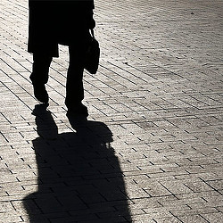 A couple of people walking on a brick road.