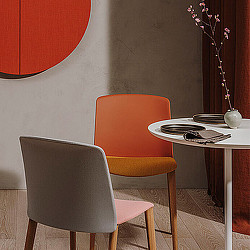 A couple of chairs next to a table with plates and a vase.