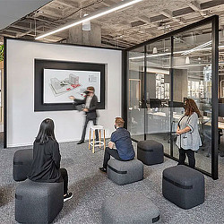 A person standing in front of a screen in a room with people.