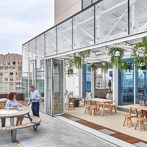 A man and woman sitting at tables outside a building.