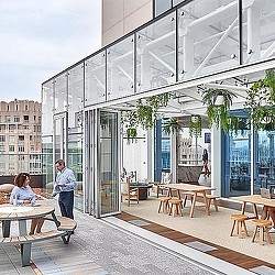 A man and woman sitting at tables outside a building.