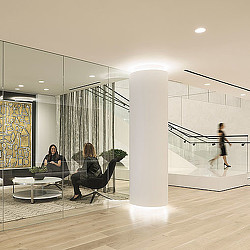 A couple of women sitting at a table in a room with a large white pillar and a couple.