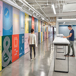 A man and a woman in a room with a desk and a computer.