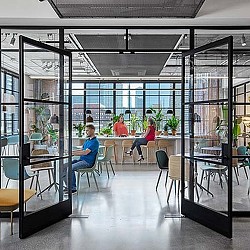 A group of people sitting at a table in a room with glass walls.