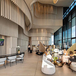 A room with a large ceiling and chairs and people sitting at tables.