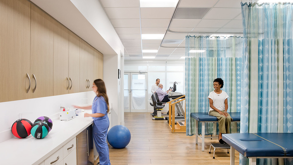 A woman standing in front of a man sitting at a desk.