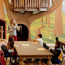 A person standing in front of a group of people sitting at a table.