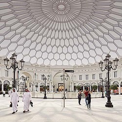 A large white building with a dome roof and people walking around.
