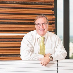 A person in a white shirt and yellow tie sitting on a bench.