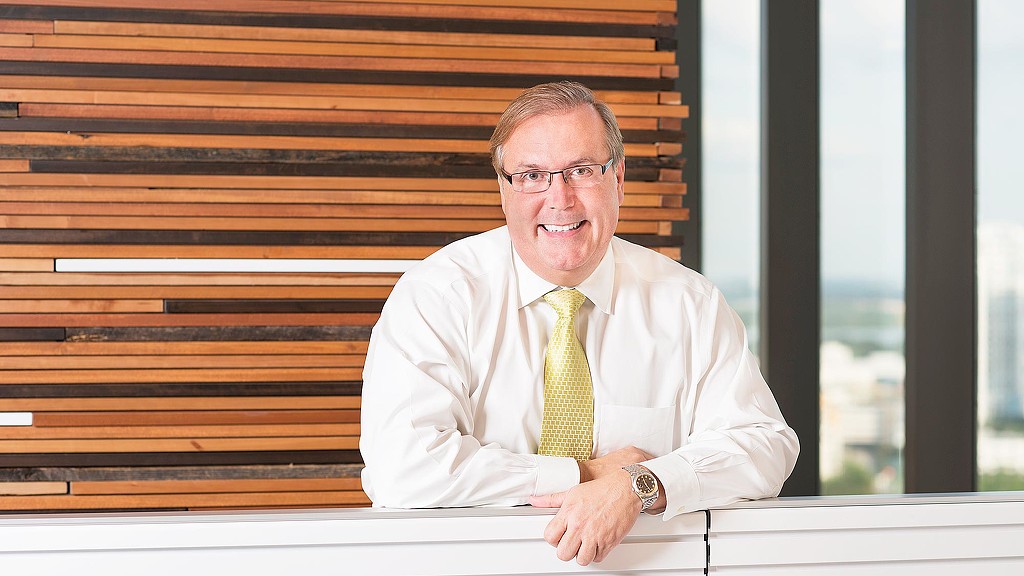 A person in a white shirt and yellow tie sitting at a desk.