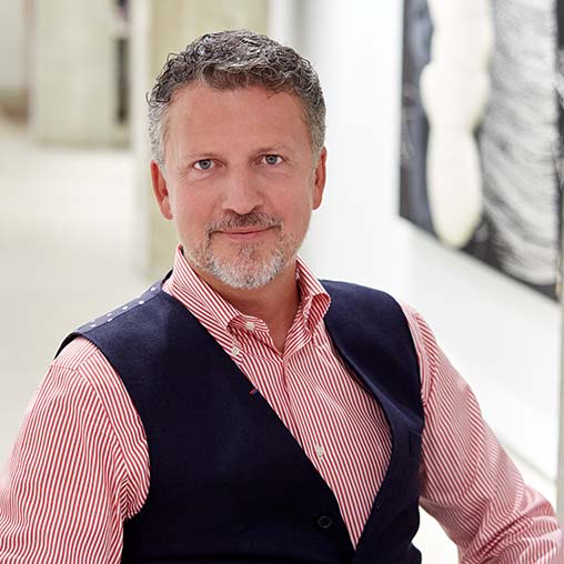 A man wearing a vest and smiling.