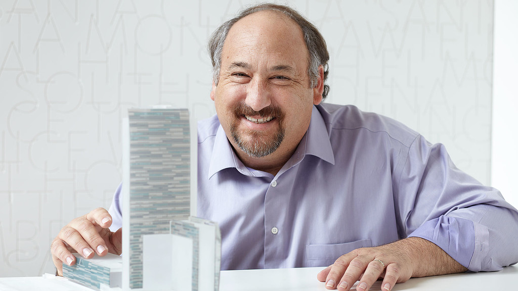 A man smiling and holding a laptop.