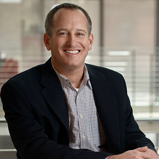 A person in a suit smiling.