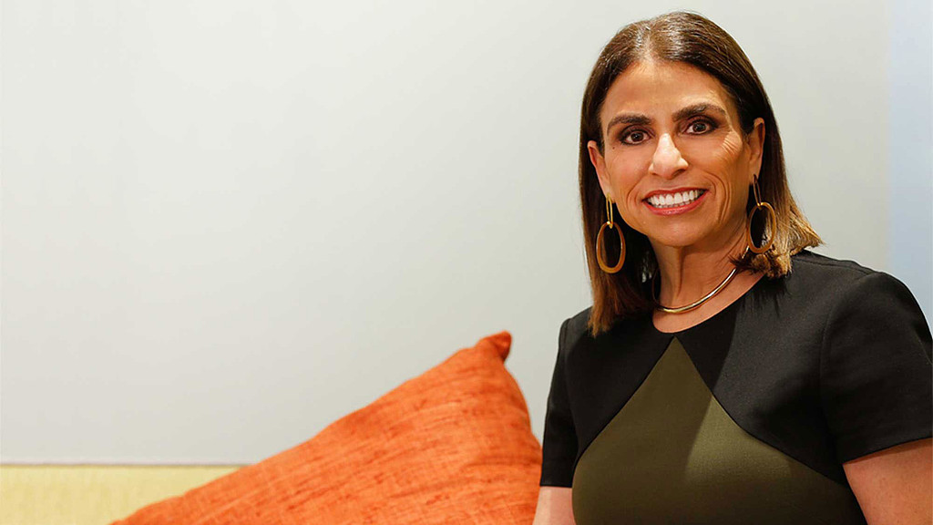 A woman smiling and wearing earrings.