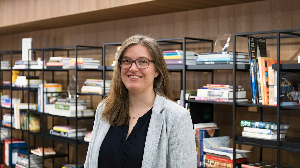 A person standing in front of a shelf of books.