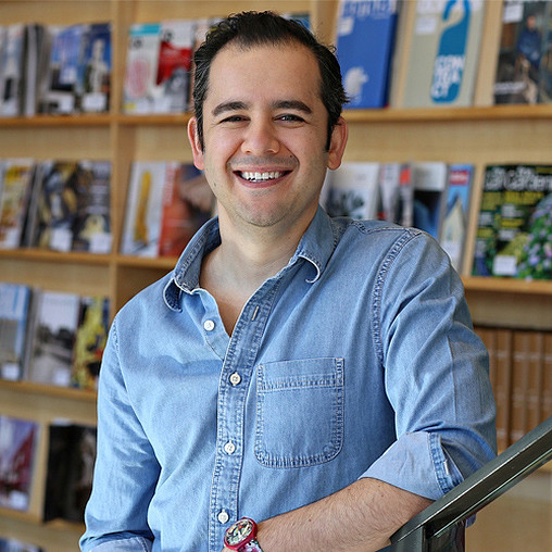 A person smiling in front of a bookshelf.