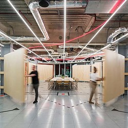 A man and woman walking in a large room with tables and chairs.