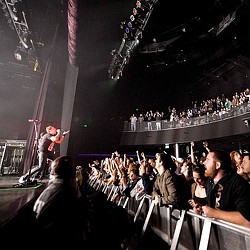 A person on a stage with a guitar in front of a crowd.