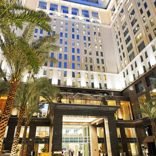 A building with a walkway and palm trees.