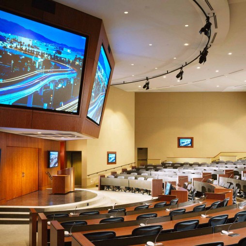 A room with tables and chairs and a large screen.